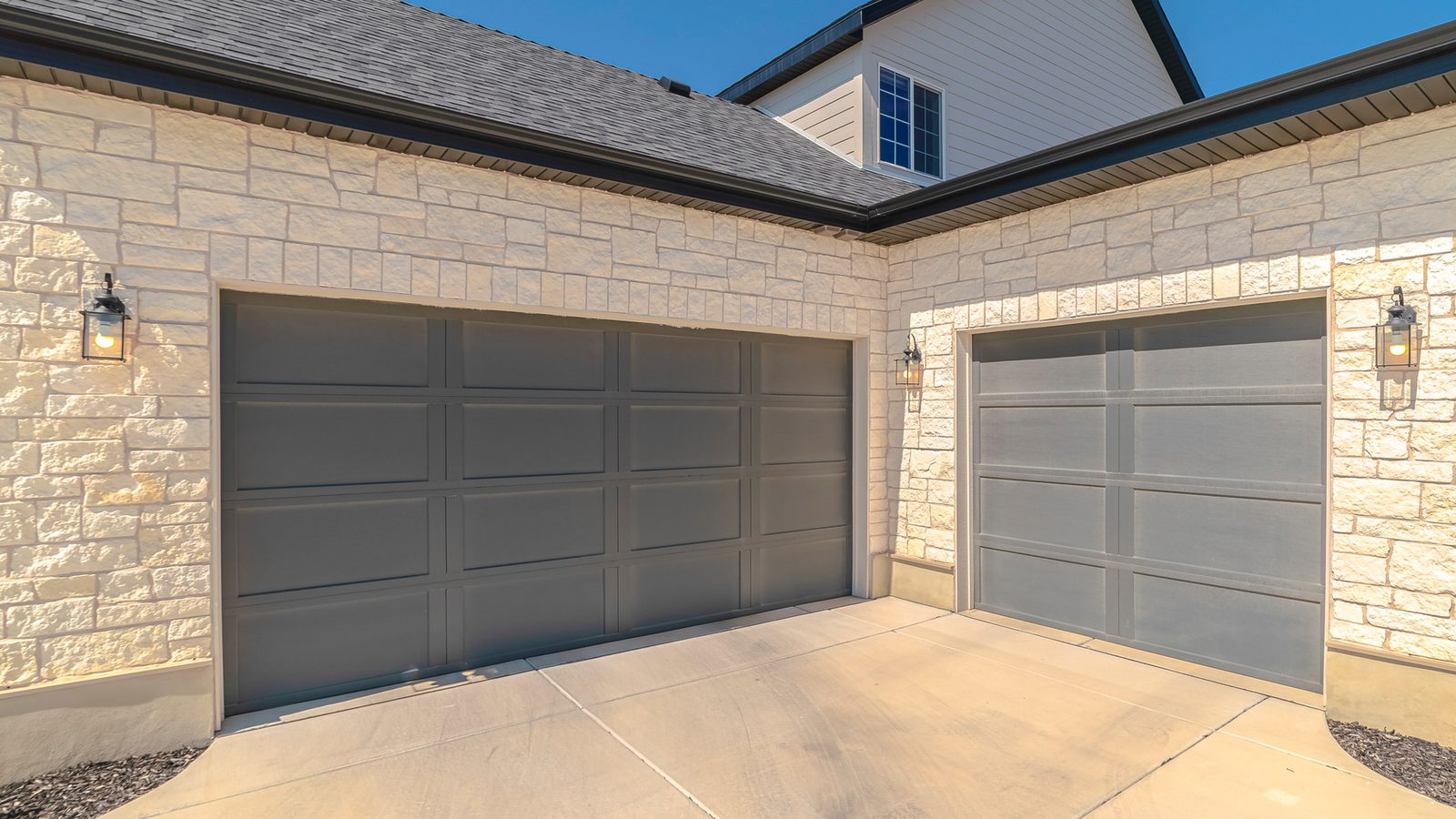 Three-car garage with gray doors on a stone suburban home